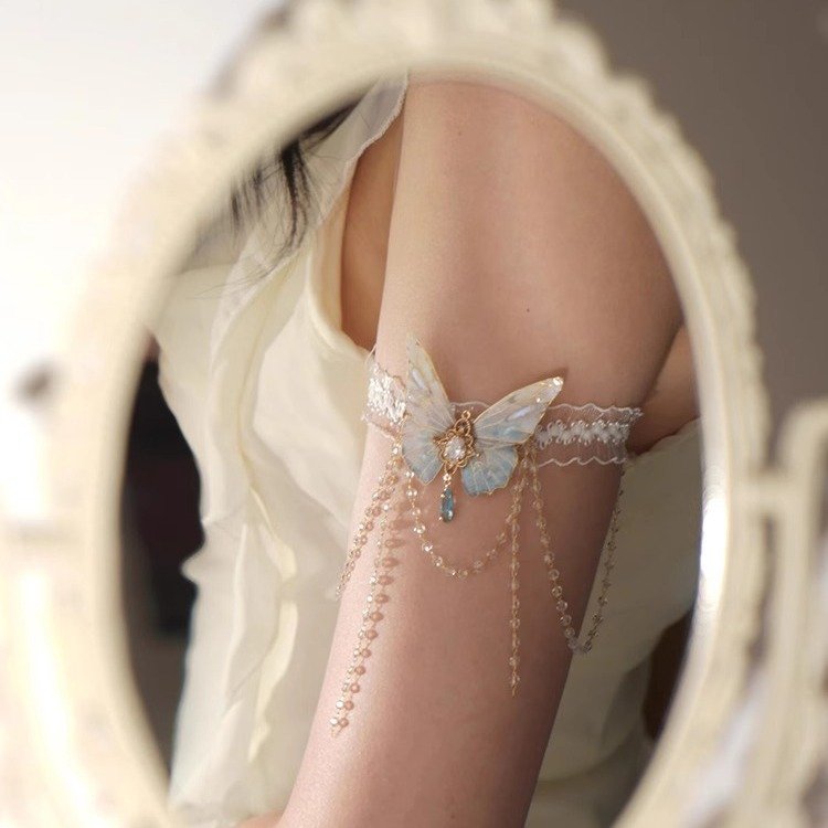 A delicate lace body chain with butterfly charms and tassels, styled on an arm