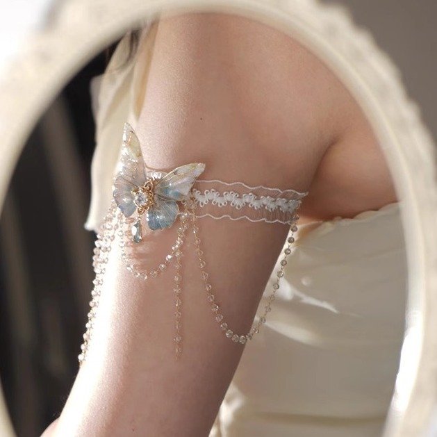 A delicate lace body chain with butterfly charms and tassels, styled on an arm 4