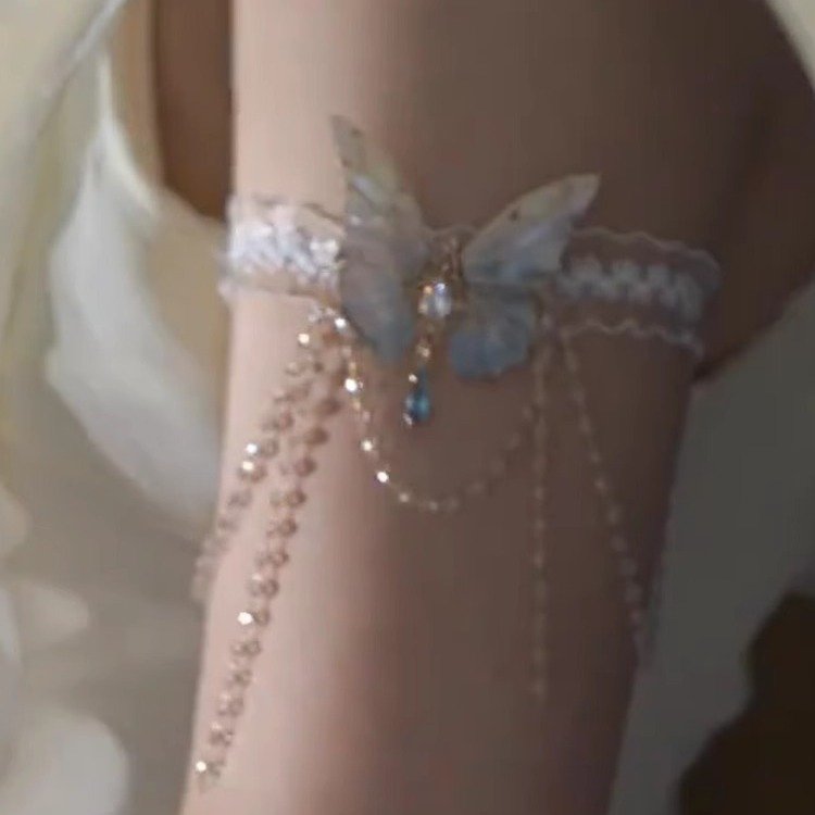 A delicate lace body chain with butterfly charms and tassels, styled on an arm 2